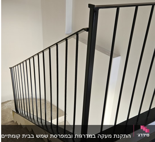 מעקה מתכת שחור על מדרגות בטון